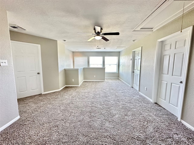 empty room featuring a textured ceiling, ceiling fan, and carpet