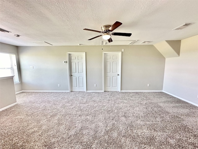 spare room with a textured ceiling, carpet flooring, and ceiling fan