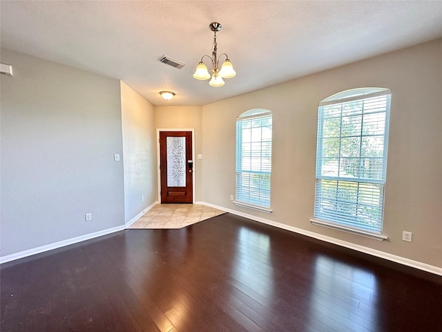 foyer entrance featuring visible vents, baseboards, an inviting chandelier, and hardwood / wood-style floors