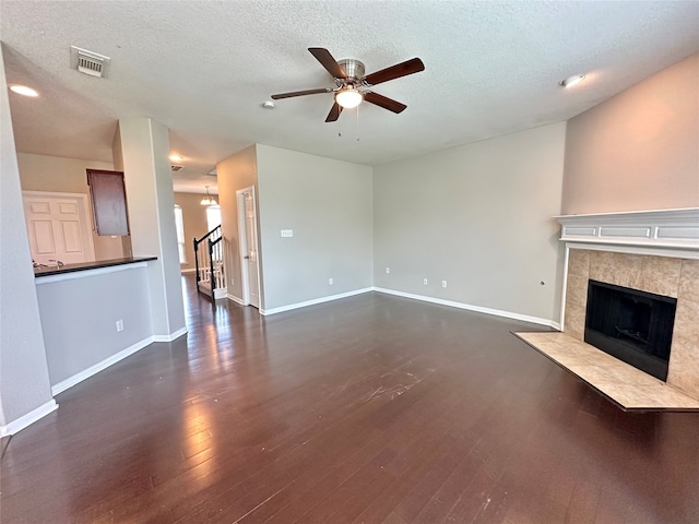 unfurnished living room featuring a fireplace, dark hardwood / wood-style flooring, ceiling fan, and a textured ceiling