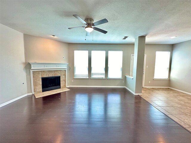 unfurnished living room with a fireplace, a textured ceiling, hardwood / wood-style flooring, and ceiling fan