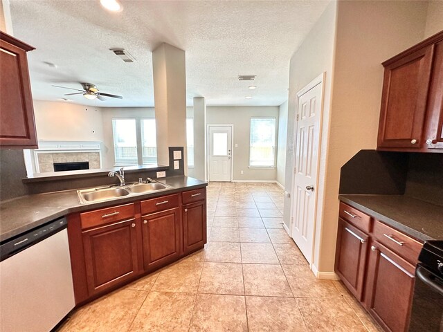 kitchen with a tiled fireplace, light tile patterned floors, dishwasher, sink, and ceiling fan