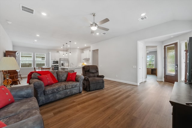 living room featuring lofted ceiling, ceiling fan, sink, and hardwood / wood-style flooring