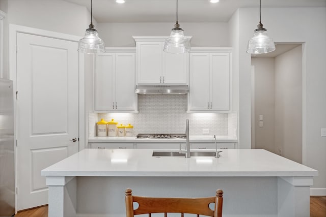 kitchen with an island with sink, decorative light fixtures, and light hardwood / wood-style floors