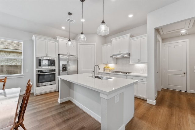 kitchen featuring light hardwood / wood-style flooring, a kitchen island with sink, stainless steel appliances, sink, and white cabinets