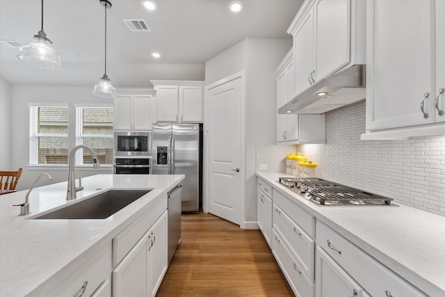 kitchen with light wood-type flooring, pendant lighting, white cabinetry, stainless steel appliances, and sink