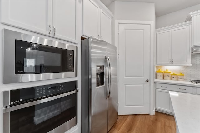 kitchen featuring white cabinets, appliances with stainless steel finishes, backsplash, and light hardwood / wood-style floors