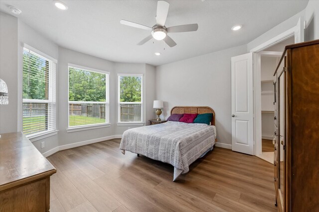 bedroom with multiple windows, hardwood / wood-style floors, and ceiling fan