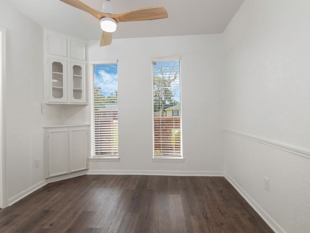 spare room featuring a wealth of natural light, dark wood-type flooring, and ceiling fan