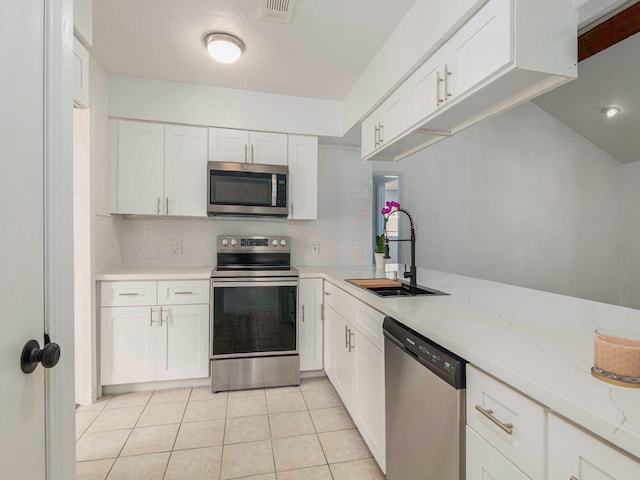 kitchen with white cabinetry, stainless steel appliances, sink, light stone countertops, and decorative backsplash