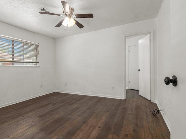 empty room featuring dark wood-type flooring, a textured ceiling, and ceiling fan