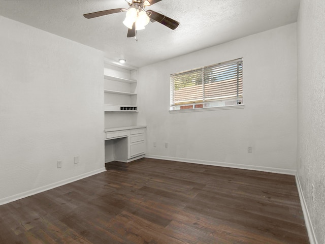 unfurnished living room with built in desk, dark hardwood / wood-style floors, built in features, ceiling fan, and a textured ceiling