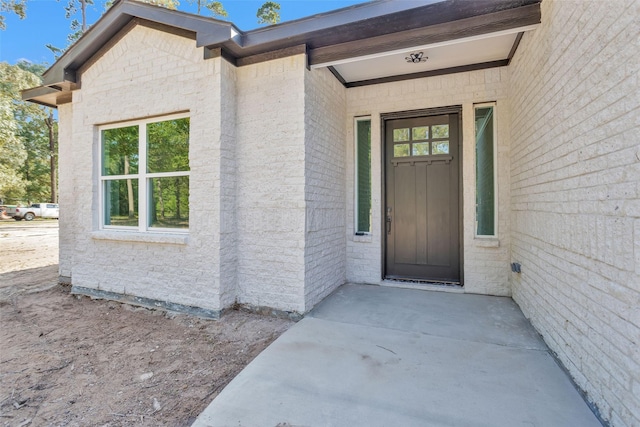 view of exterior entry featuring brick siding