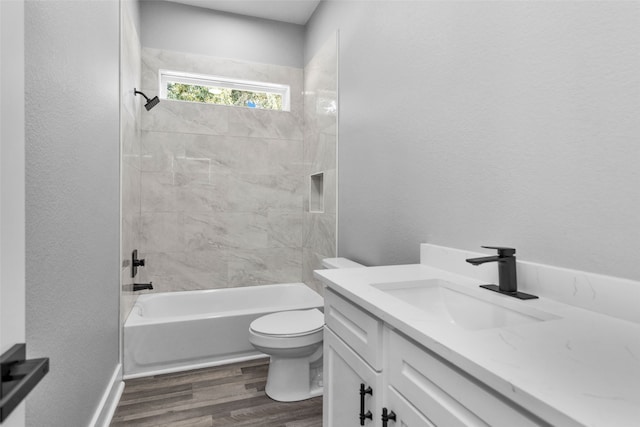 full bathroom featuring toilet, hardwood / wood-style flooring, tiled shower / bath combo, and vanity