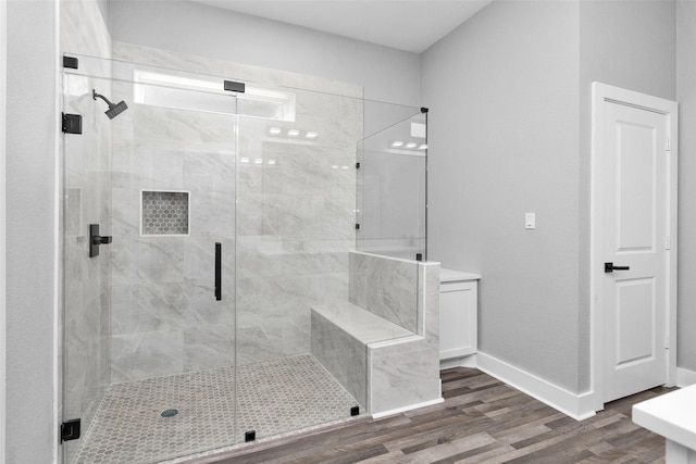 bathroom with a stall shower, baseboards, and wood finished floors