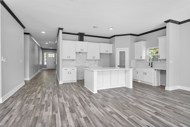 kitchen featuring white cabinets, plenty of natural light, light hardwood / wood-style floors, and ornamental molding