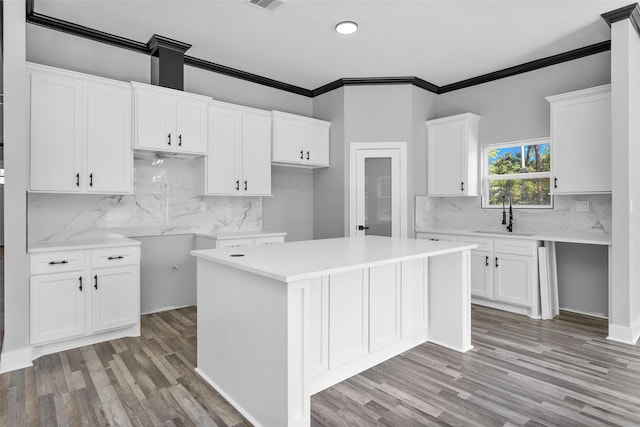 kitchen featuring light wood finished floors, a sink, white cabinetry, and a center island