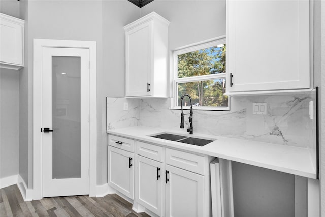 kitchen with hardwood / wood-style floors, light stone countertops, tasteful backsplash, and sink