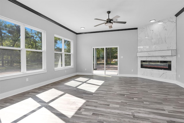 unfurnished living room featuring recessed lighting, a premium fireplace, wood finished floors, baseboards, and ornamental molding