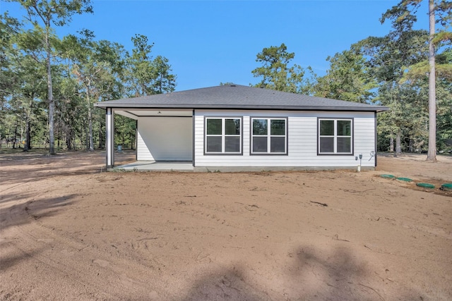 rear view of property featuring roof with shingles and a patio area