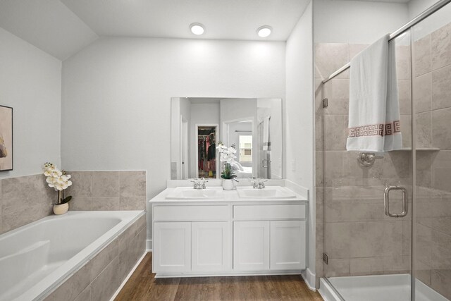 bathroom with hardwood / wood-style floors, separate shower and tub, vaulted ceiling, and vanity