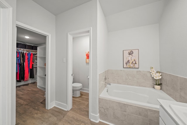 bathroom featuring vanity, toilet, a relaxing tiled tub, and hardwood / wood-style floors