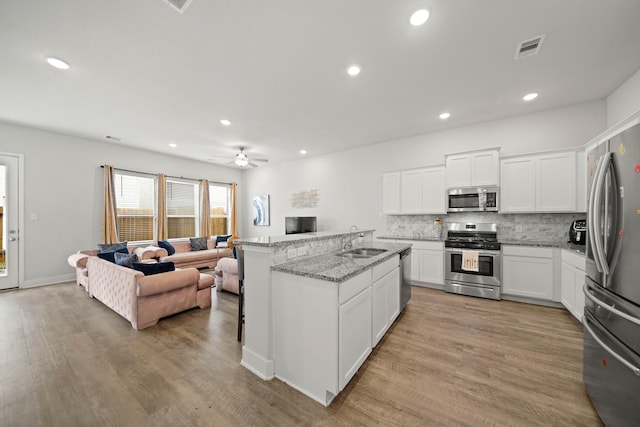 kitchen featuring light hardwood / wood-style flooring, appliances with stainless steel finishes, sink, ceiling fan, and white cabinets