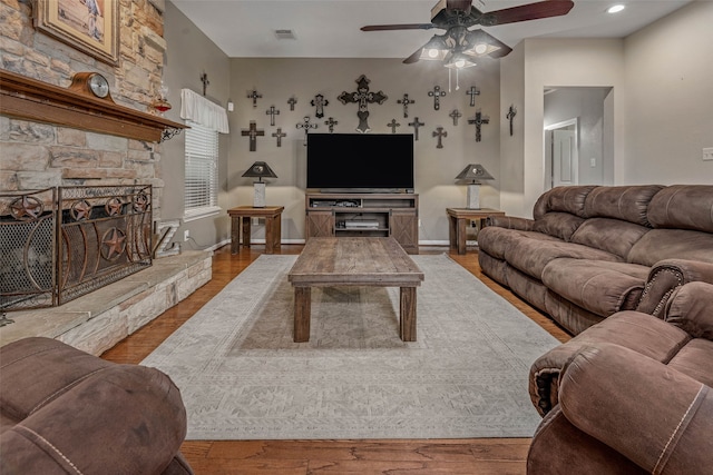 living room featuring ceiling fan, a fireplace, and light hardwood / wood-style floors