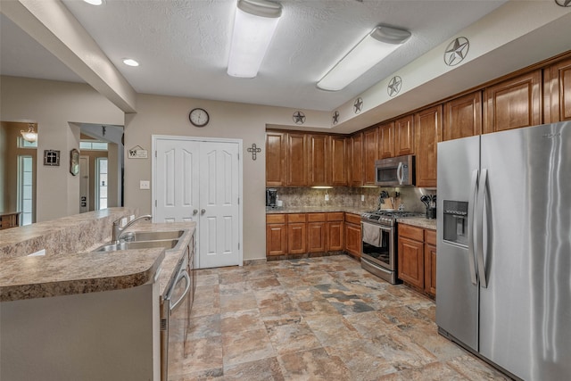 kitchen with a textured ceiling, backsplash, light tile patterned floors, sink, and appliances with stainless steel finishes