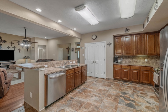 kitchen with stainless steel appliances, sink, decorative backsplash, ceiling fan, and light hardwood / wood-style floors