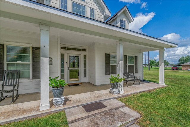 entrance to property with covered porch and a lawn