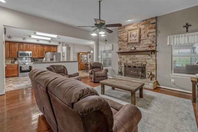 living room with light wood-type flooring, a fireplace, and ceiling fan