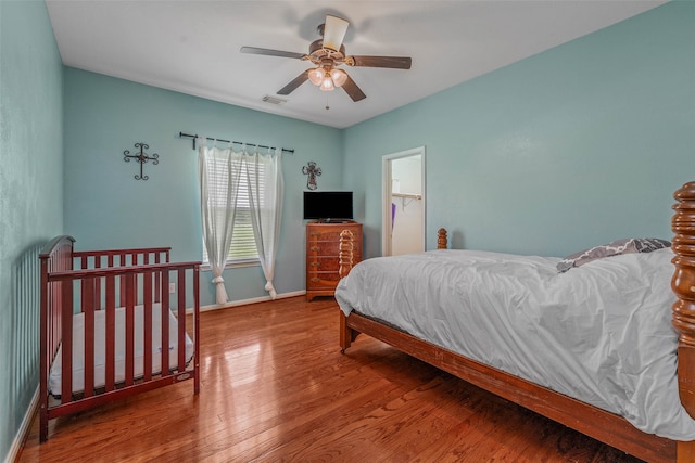 bedroom with ceiling fan, a walk in closet, and wood-type flooring