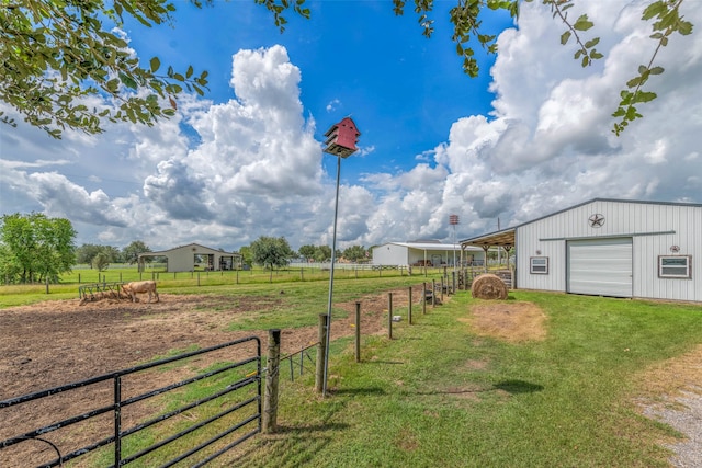 view of yard with a garage, a rural view, and an outdoor structure