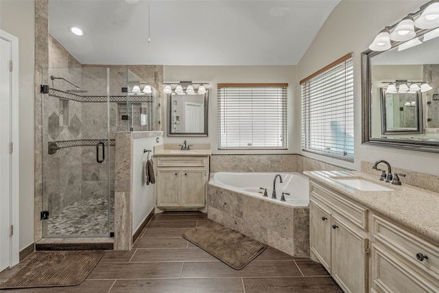 bathroom with vanity, vaulted ceiling, and independent shower and bath