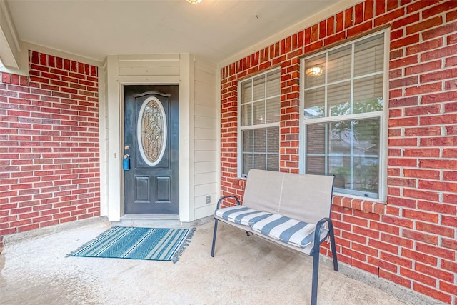 entrance to property with covered porch and brick siding