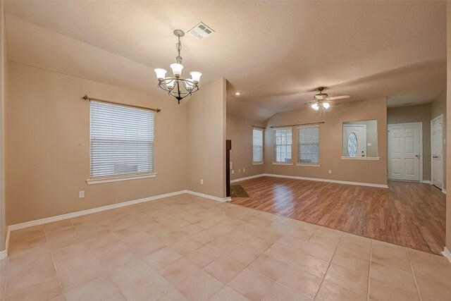 empty room featuring light tile patterned floors, baseboards, vaulted ceiling, and ceiling fan with notable chandelier