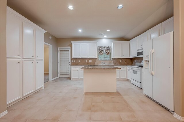 kitchen with white appliances, tasteful backsplash, white cabinets, a center island, and recessed lighting