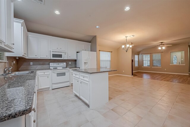 kitchen featuring white appliances, open floor plan, a sink, vaulted ceiling, and backsplash