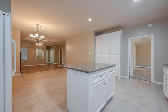 kitchen with a chandelier, stone counters, white cabinetry, hanging light fixtures, and a center island