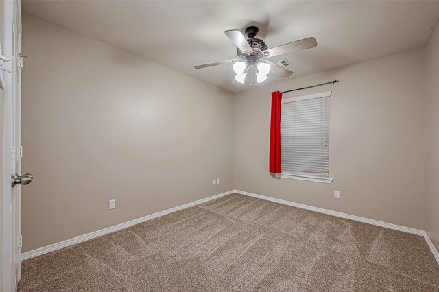 carpeted spare room featuring visible vents, baseboards, and ceiling fan