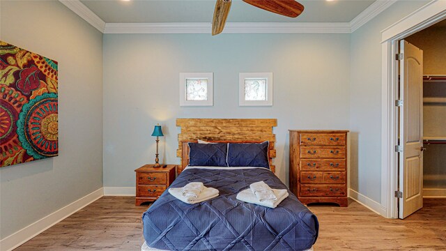 bedroom with a closet, hardwood / wood-style floors, crown molding, a spacious closet, and ceiling fan