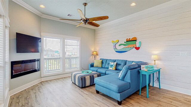 living room with ornamental molding, light wood-type flooring, and ceiling fan