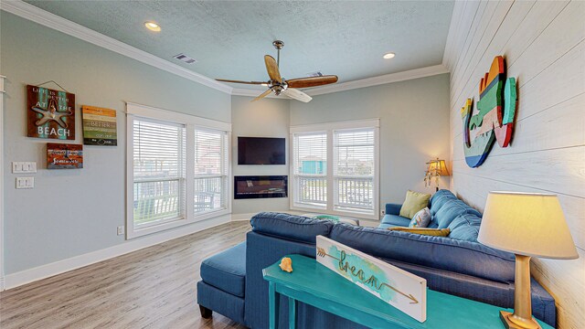 living room featuring ceiling fan, a textured ceiling, hardwood / wood-style flooring, and a healthy amount of sunlight