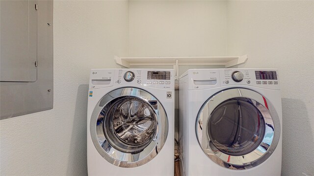 clothes washing area with washer and clothes dryer and electric panel