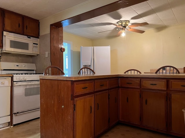 kitchen featuring white appliances, kitchen peninsula, and ceiling fan