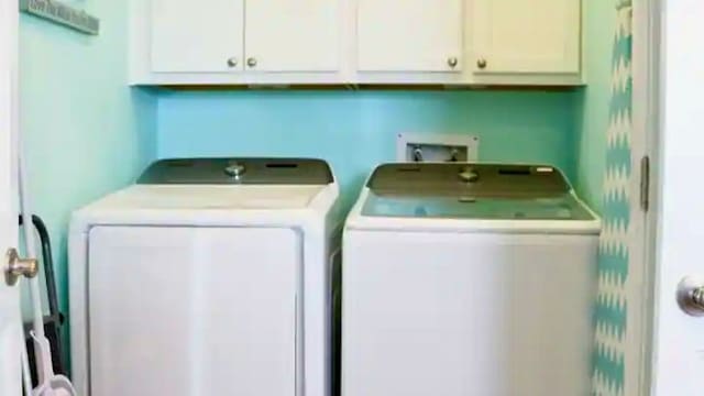 clothes washing area featuring cabinets and washer and clothes dryer