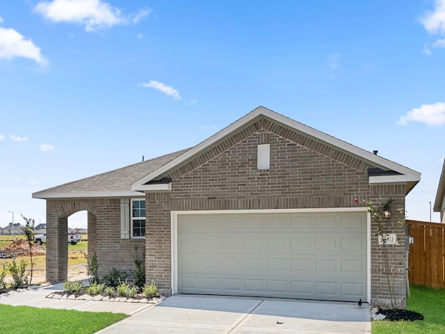 ranch-style house with a garage, brick siding, fence, driveway, and roof with shingles