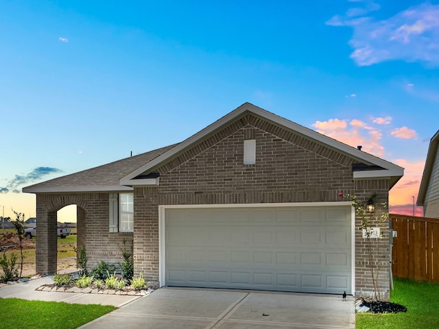 ranch-style house featuring a garage, driveway, brick siding, and fence