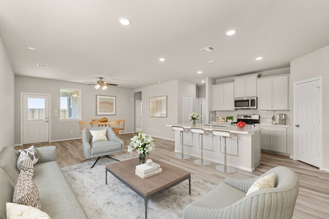 living room with light wood-type flooring and ceiling fan